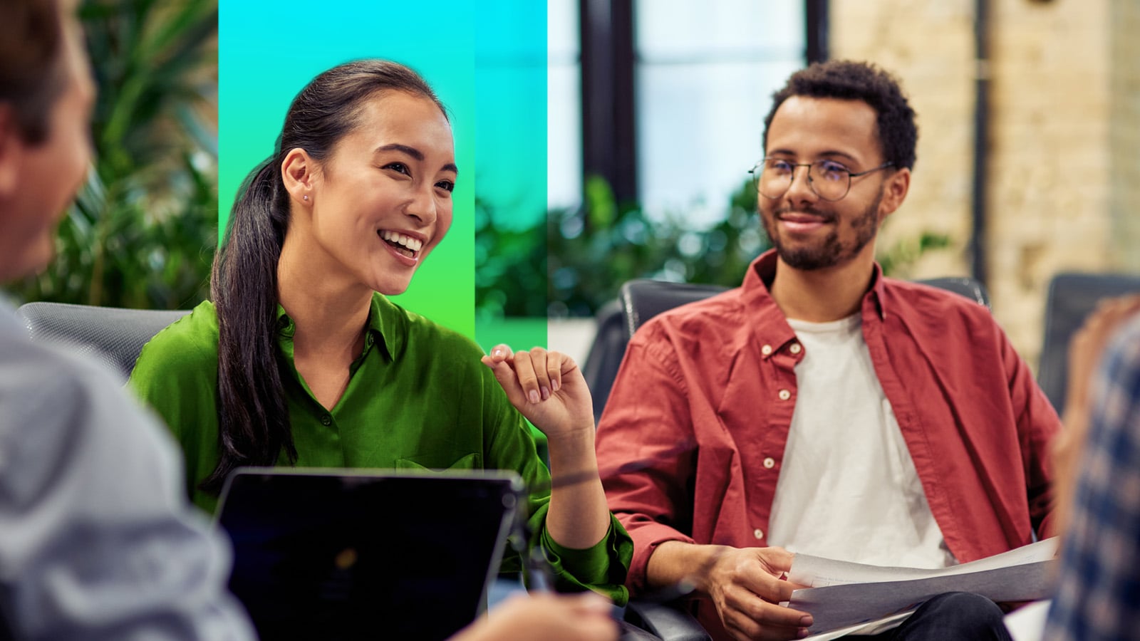 Young men and women professionals in casual attire with their laptops talking and smiling in an office environment